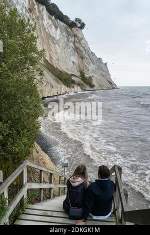 Scogliere di gesso 'øns Klint', Mar Baltico, costa ripida con una spiaggia allagata, coppia seduto sulle scale da dietro Foto Stock