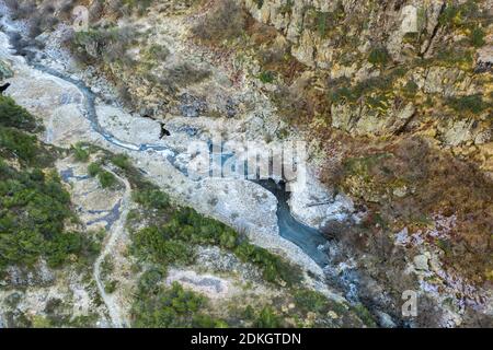 Scatti aerei di ruscello di montagna alla linea dell'albero dentro le alte montagne Foto Stock