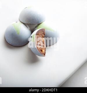 dome shaped chocolate candy bonbons stuffed with sesame praline. Decorated with a little christmas tree on white background. Exclusive handcrafted bon Stock Photo