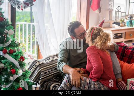 Coppia adulta persone caucasiche in amore baciare e condividere la dolcezza a casa durante le vacanze invernali di natale - concetto di celebrazione e la vita insieme per sempre con felice uomo e donna bacio l'uno con l'altro Foto Stock