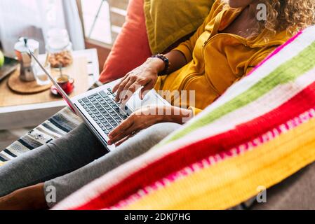 Donna irriconoscibile lavora a casa con un computer portatile seduto il divano - persone e tecnologia shopping on line concetto per eventi online di black friday o cyber monday Foto Stock