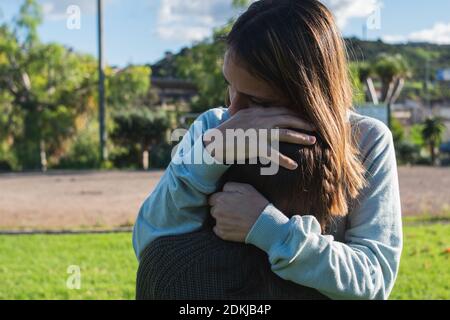 Madre abbracciando la sua figlia triste, mentre sta piangendo, per consolarla Foto Stock