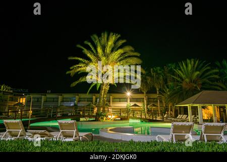 Vista sulla piscina dell'hotel con palme e bar della piscina di notte in estate. Hotel Belorizonte a Cabo Verde Santa Maria Salt Island Foto Stock