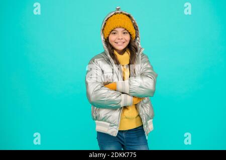 felice capretto in giacca di puffer d'argento e maglieria ottenere caldo in inverno pronto per l'attività in vacanza, vacanze di natale. Foto Stock