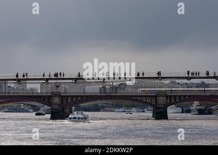 Pedoni sul Millennium Bridge sul Tamigi, con il Blackfriars Railway Bridge alle spalle. Londra, Regno Unito Foto Stock