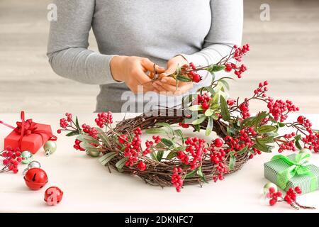 Donna che fa bella corona di Natale a tavola Foto Stock