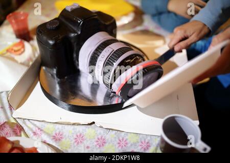 Donna che taglia la torta sotto forma di macchina fotografica Foto Stock