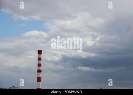 I camini della fabbrica inquinano l'aria, fumo spesso dipinto dal tramonto, il crepuscolo serale del cielo. Bellissimo paesaggio industriale verticale, ambientale prob Foto Stock