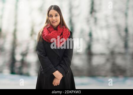 UNA GIOVANE DONNA IN STRACCIO D'INVERNI IN PIEDI E SORRIDENTE Foto Stock