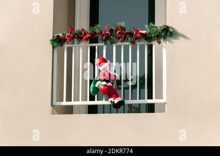 Santa coperta di neve sale il balcone sulla corda Foto Stock