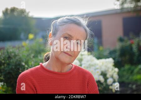 Bella vecchia nonna con capelli grigi e viso con rughe relax all'aperto nel parco durante la giornata di sole Foto Stock