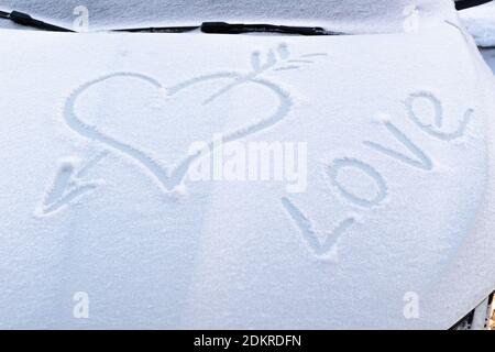 immagine di un cuore rotto con una freccia nel neve sul cofano di un'auto su una gelata giorno invernale Foto Stock