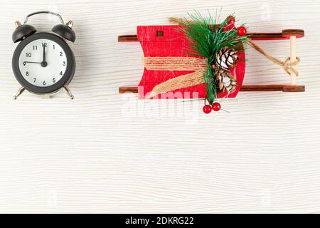 sveglia in custodia nera e slitta rossa di babbo natale su sfondo di legno bianco con vene d'oro Foto Stock