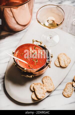 Caviale rosso in piatti di rame metallico con cracker salati e bicchiere di champagne su tavolo di marmo bianco, vista dall'alto. Concetto di umore per le vacanze invernali Foto Stock