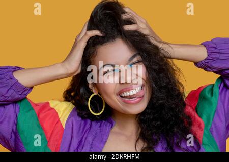 Carino ragazza dai capelli scuri in giacca luminosa sorridente felicemente Foto Stock