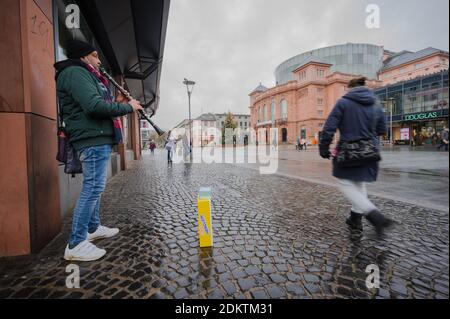 Magonza, Germania. 16 Dic 2020. Un musicista di strada suona nel centro della città. Ludwigstraße è quasi deserta durante i consueti orari di apertura del negozio. Numerosi negozi rimangono chiusi a causa della chiusura a livello nazionale. L'obbligo di frequentare le scuole viene revocato. Credit: Andreas Arnold/dpa/Alamy Live News Foto Stock