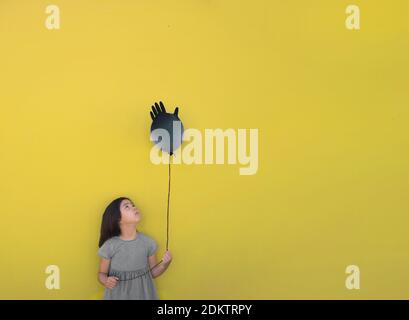 Una ragazza triste tiene un guanto gonfiato in mano invece di un pallone, è il suo compleanno durante la pandemia del coronovirus. Banner Foto Stock