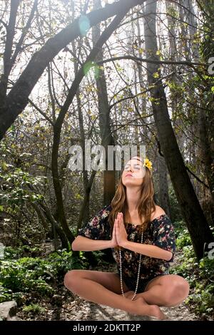 Teen Hippie ragazza medita all'aperto in una foresta Foto Stock