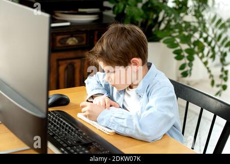 Apprendimento a distanza durante l'isolamento durante la quarantena nel coronovirus. Ragazzo e laptop a casa. Stile di vita. Foto Stock