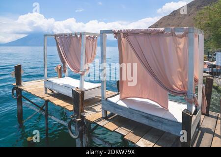 Due letti a baldacchino sul molo di legno lungo il lago Atitlan alla costa di Santa Cruz la Laguna, Guatemala Foto Stock