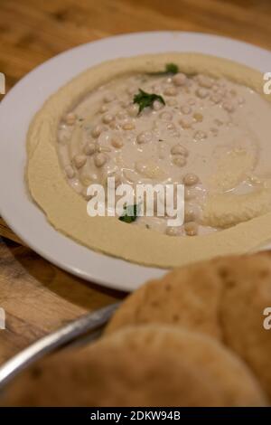 Una porzione di humus, tahini, olio d'oliva e prezzemolo una pasta mediorientale a base di ceci Foto Stock