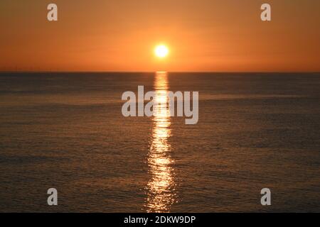 Splendido tramonto sul mare con cielo arancione e acque calme riflettenti, vicino a Brighton, Sussex, Inghilterra, Regno Unito Foto Stock