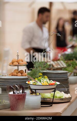 Un assortimento di cibi in ciotole su un tavolo a buffet durante un evento serale Foto Stock