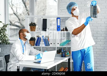 Due medici di sesso maschile esaminano la risonanza magnetica cerebrale di un paziente nel cabinet Foto Stock