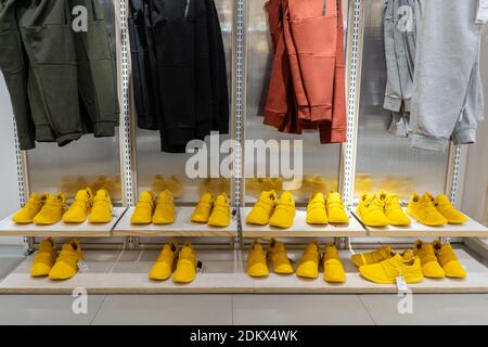 File di sneakers gialli, pantaloni appesi su di loro. Colori grigio e giallo 2021. Foto Stock