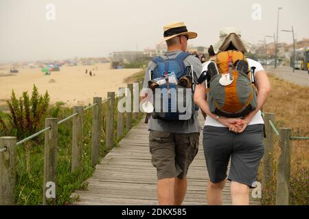 Un paio di pellegrini che camminano su una passerella durante il loro pellegrinaggio lungo il Camino de Santiago Portugués (Via Portoghese di San Giacomo). Foto Stock