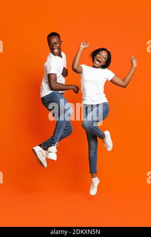 Spensierato uomo e donna africani che danzano sull'arancio Foto Stock