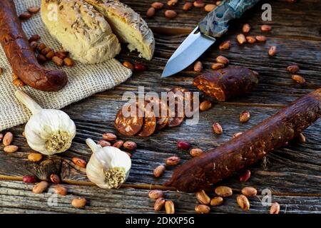 Salsiccia fatta in casa con pane e coltello su tavola rustica vista dall'alto Foto Stock