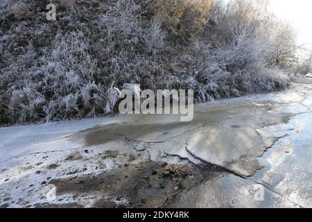 Curva ghiacciata su una strada in rovina in inverno. Foto Stock