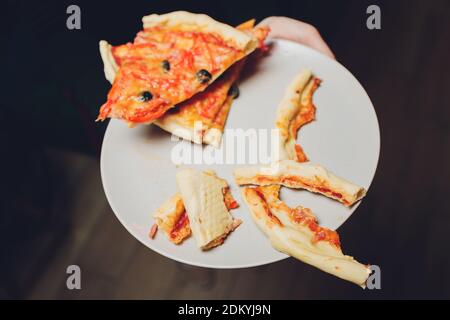 Poche fette di pizza hawaiana mangiata a metà, composizione Foto Stock