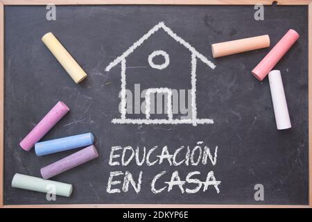 Scuola a domicilio in spagnolo su una lavagna con alcuni gessi su di essa. Modello educativo alternativo. Foto Stock