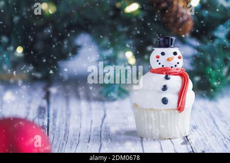 Ciced allegro Natale cupcake Snowman con naso di carota, cappello di santa, e sciarpa. Messa a fuoco selettiva con primo piano e sfondo sfocati. Foto Stock