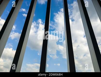 Cielo blu con vista nuvolosa attraverso la griglia metallica sulla terrazza dell'edificio degli uffici in città. Foto Stock