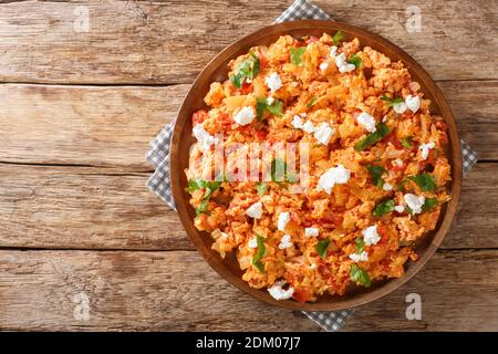 Delicious scrambled eggs with tomatoes and feta cheese close-up in a plate on the table. horizontal top view from above Foto Stock
