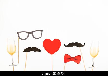 San Valentino lgbt, amore, concetto di matrimonio. Cuore rosso, bicchieri di champagne con baffi di carta di coppia su sfondo rosa. Biglietto d'auguri. Disposizione piatta Foto Stock