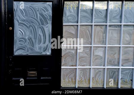 primo piano di un piccolo cristallo e di una porta coperta con detergente per cristalli. Negozio vuoto con finestre coperte Foto Stock