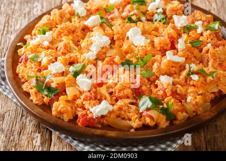 Deliziose uova strapazzate con pomodori e formaggio feta primo piano in un piatto sul tavolo. Orizzontale Foto Stock