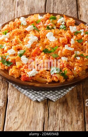 Uova strapazzate greche con pomodori e formaggio feta primo piano in un piatto sul tavolo. Verticale Foto Stock