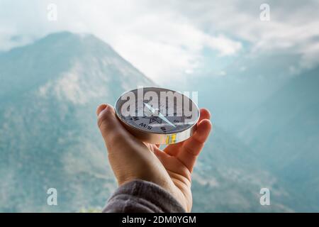 Bussola rotonda in mano sullo sfondo della montagna sfocata. Concetto di viaggio e stile di vita attivo. Nepal, Himalaya Foto Stock