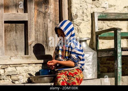 Jhong, Nepal - 8 novembre 2015: Ragazzo nepalese tagliando patate vicino a casa sua. Foto Stock