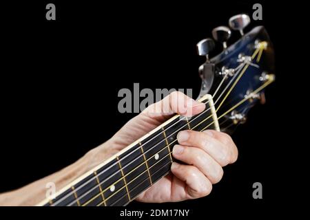 Uomo che suona su chitarra acustica. Dita di primo piano sul collo della chitarra. Isolato su nero. Messa a fuoco superficiale. Foto Stock