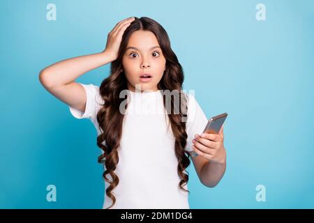 Primo piano ritratto di lei bella attraente stupito perplesso confuso ragazza con capelli ondulati che utilizza il dispositivo di navigazione lettura di notizie false isolato luminoso vivido Foto Stock