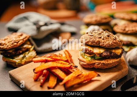 Hamburger fatto in casa a bassa dieta di carb con focacce di farina di semi e patatine di zucca. Hamburger di dieta con salsa senza zucchero, maionese, lattuga, e formaggio fuso. Ape Foto Stock