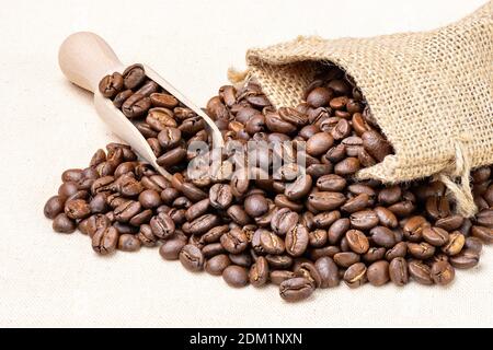 Sacchetto con chicchi di caffè appena tostati isolati su un panno bianco. Foto Stock