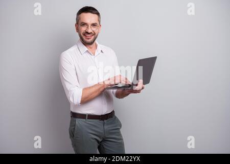 Ritratto del suo bello attraente allegro allegria successo maturo uomo che tiene in mani laptop creazione di presentazione web design isolato sopra la luce Foto Stock