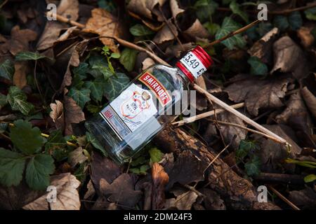 Una bottiglia di vodka vuota scartata, mezza bottiglia di vodka Smirnoff No21 giacente sul pavimento come lettiera Foto Stock